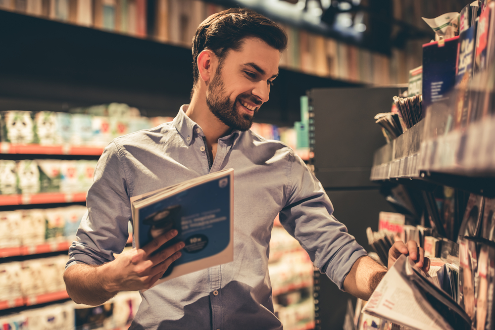 Man,Is,Choosing,A,Magazine,And,Smiling,While,Doing